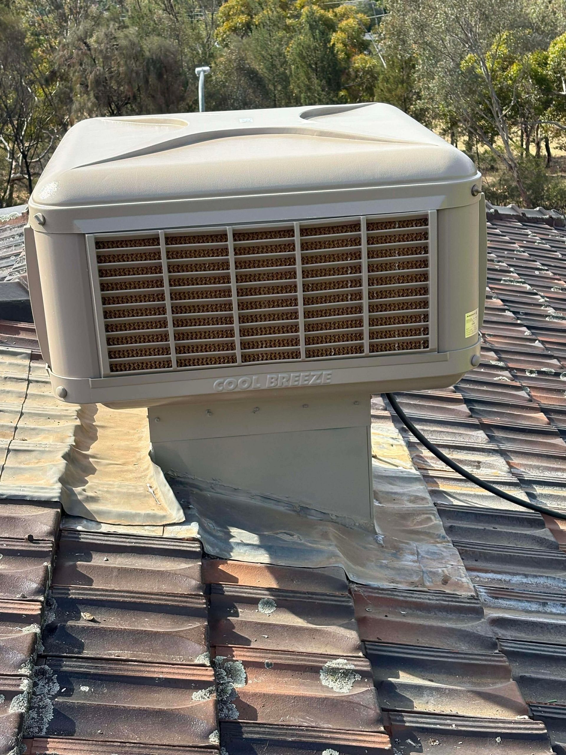Rooftop With a Solar Panel Array and Air Cooler, With Trees — Craig Stewart Electrical in East Wagga Wagga, NSW
