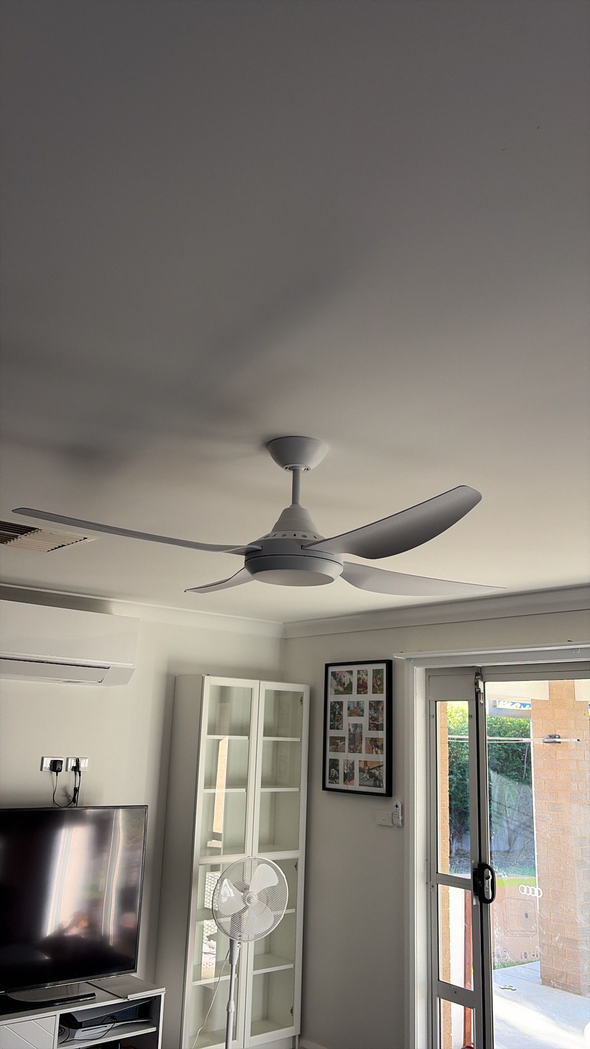Living room ceiling fan, wall-mounted TV, and open door to a bright outdoor patio. — Craig Stewart Electrical in East Wagga Wagga, NSW