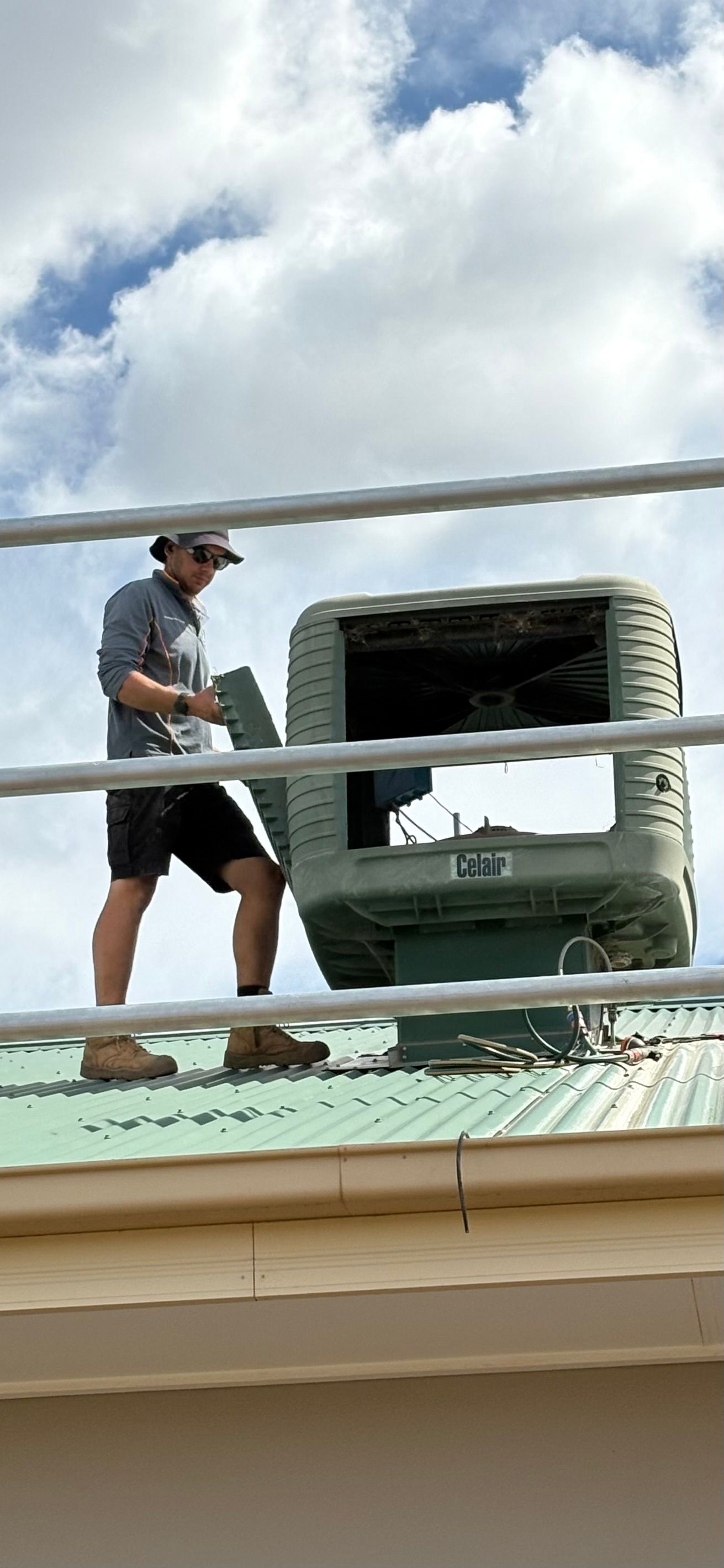 Black Evaporative Cooler on Corrugated Metal Roof, Clear Blue Sky — Craig Stewart Electrical in East Wagga Wagga, NSW