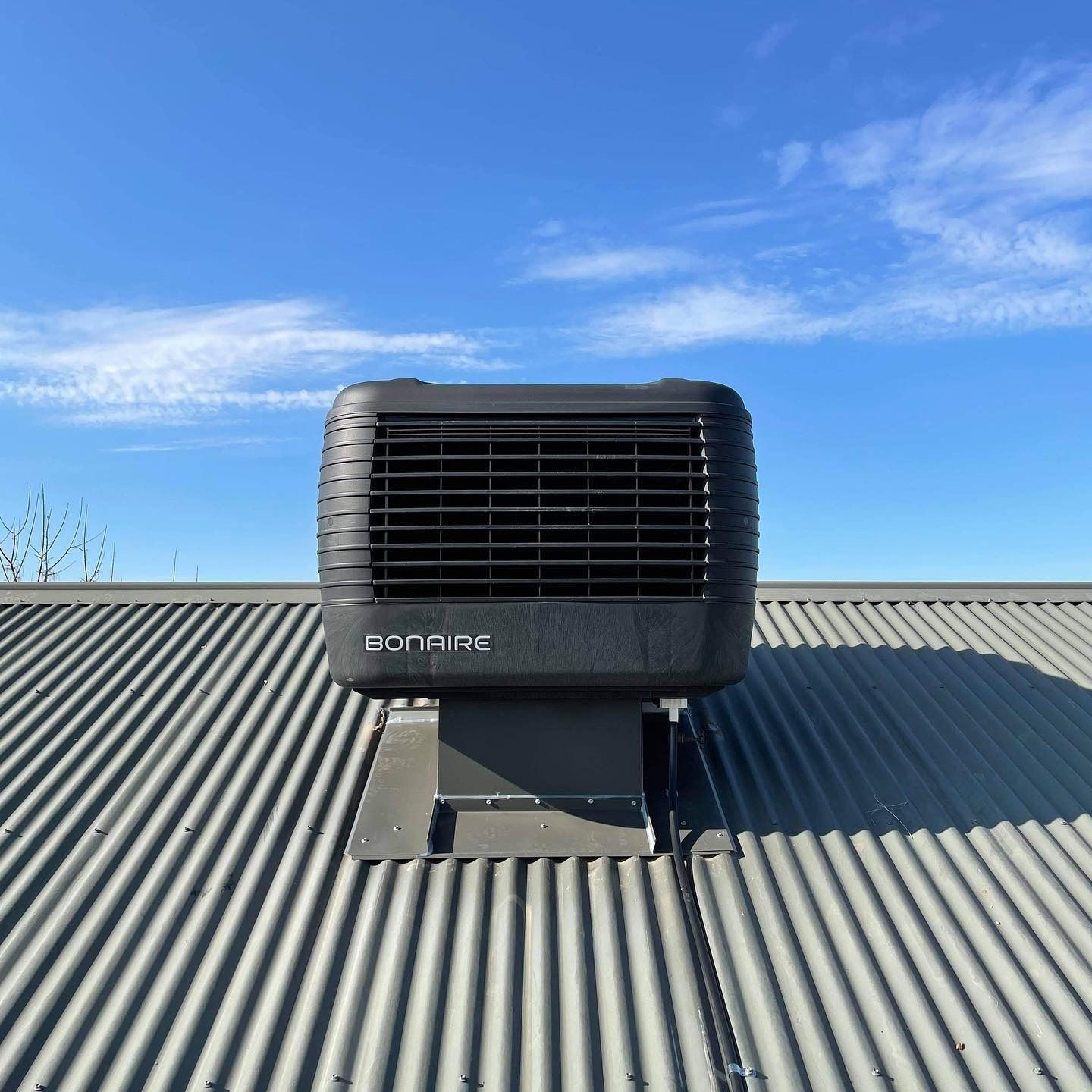 Black rooftop vent unit on a corrugated metal roof under a blue sky — Craig Stewart Electrical in East Wagga Wagga, NSW