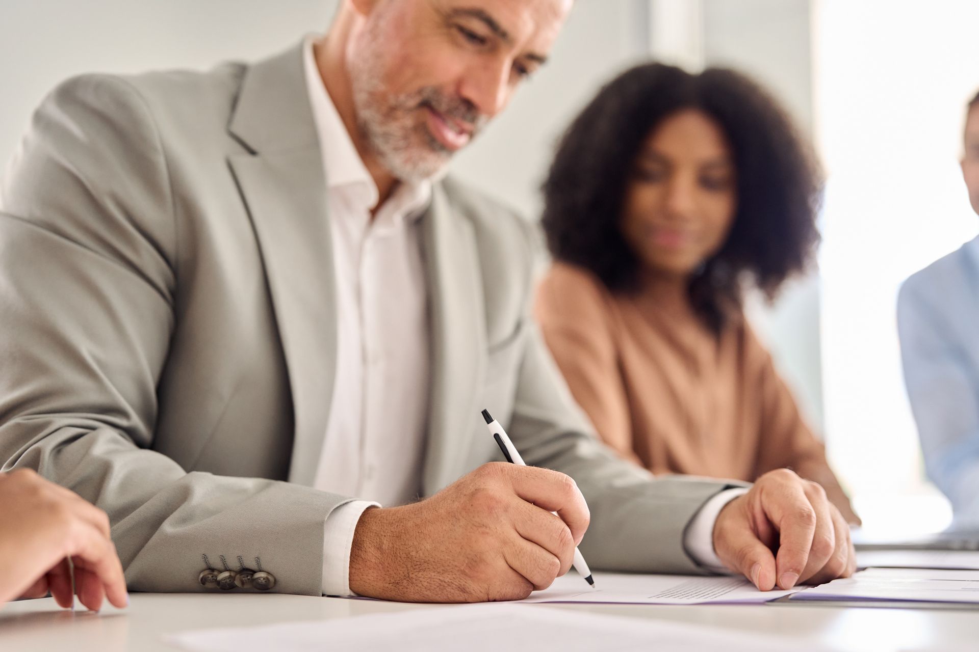 People signing documents at a table during a meeting
