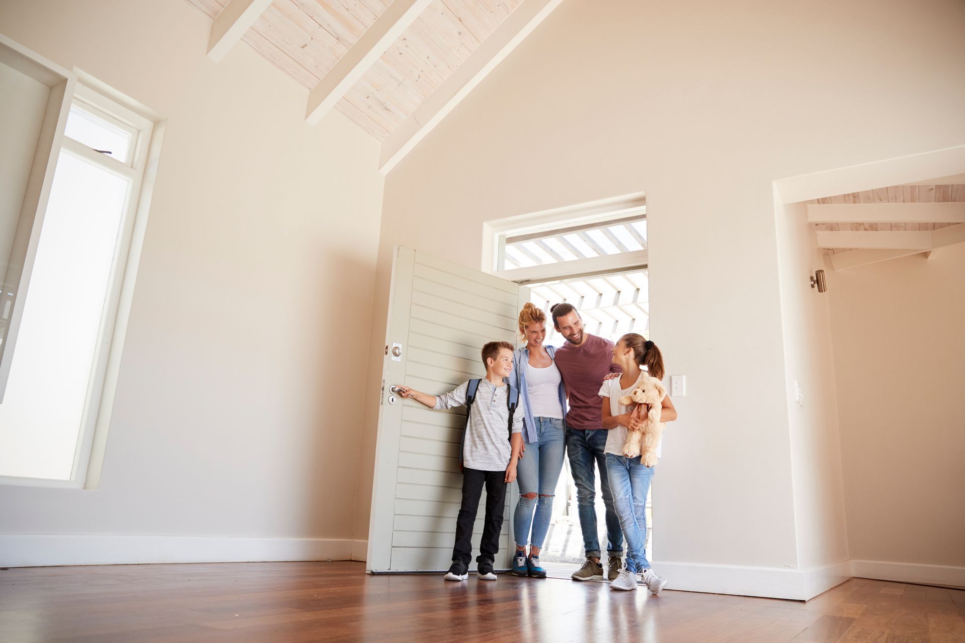 Group standing in a bright, empty room with white walls and hardwood floors.