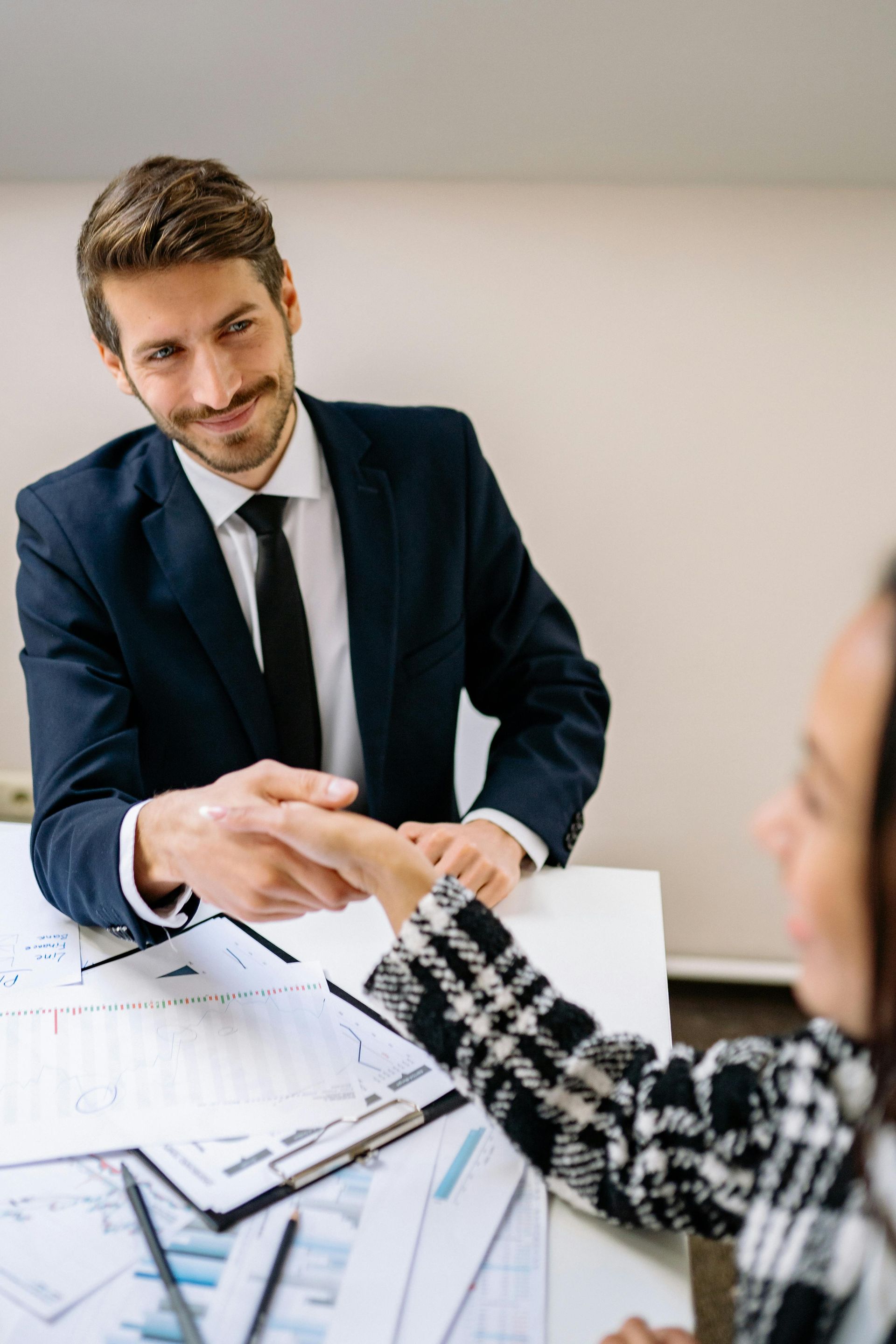 Businessman shaking hands across a desk with a colleague in a meeting room