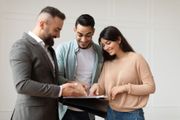 Three people smiling and reviewing a document together indoors
