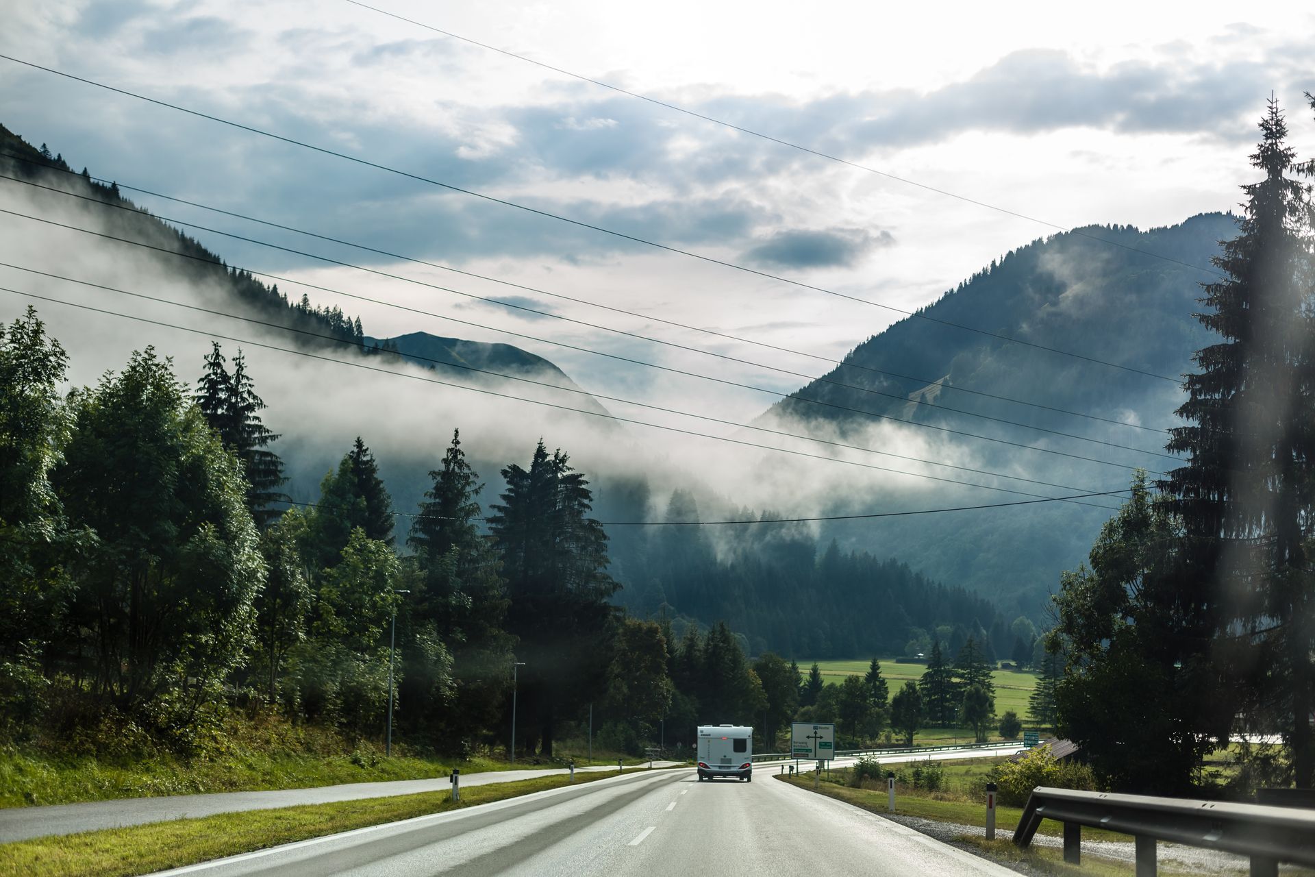 Mountain highway through a misty forest valley under cloudy skies