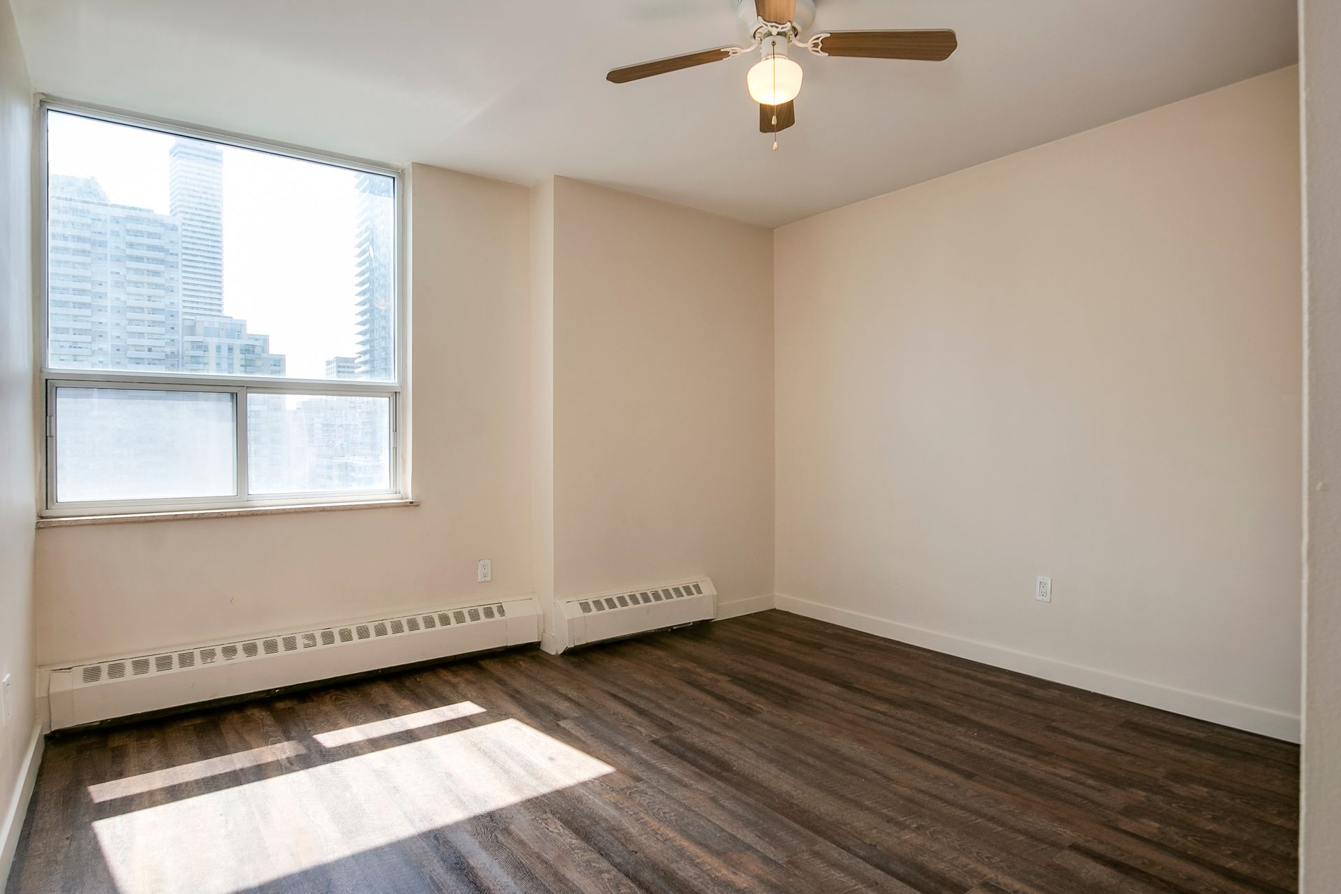 An empty room with a ceiling fan and a window.