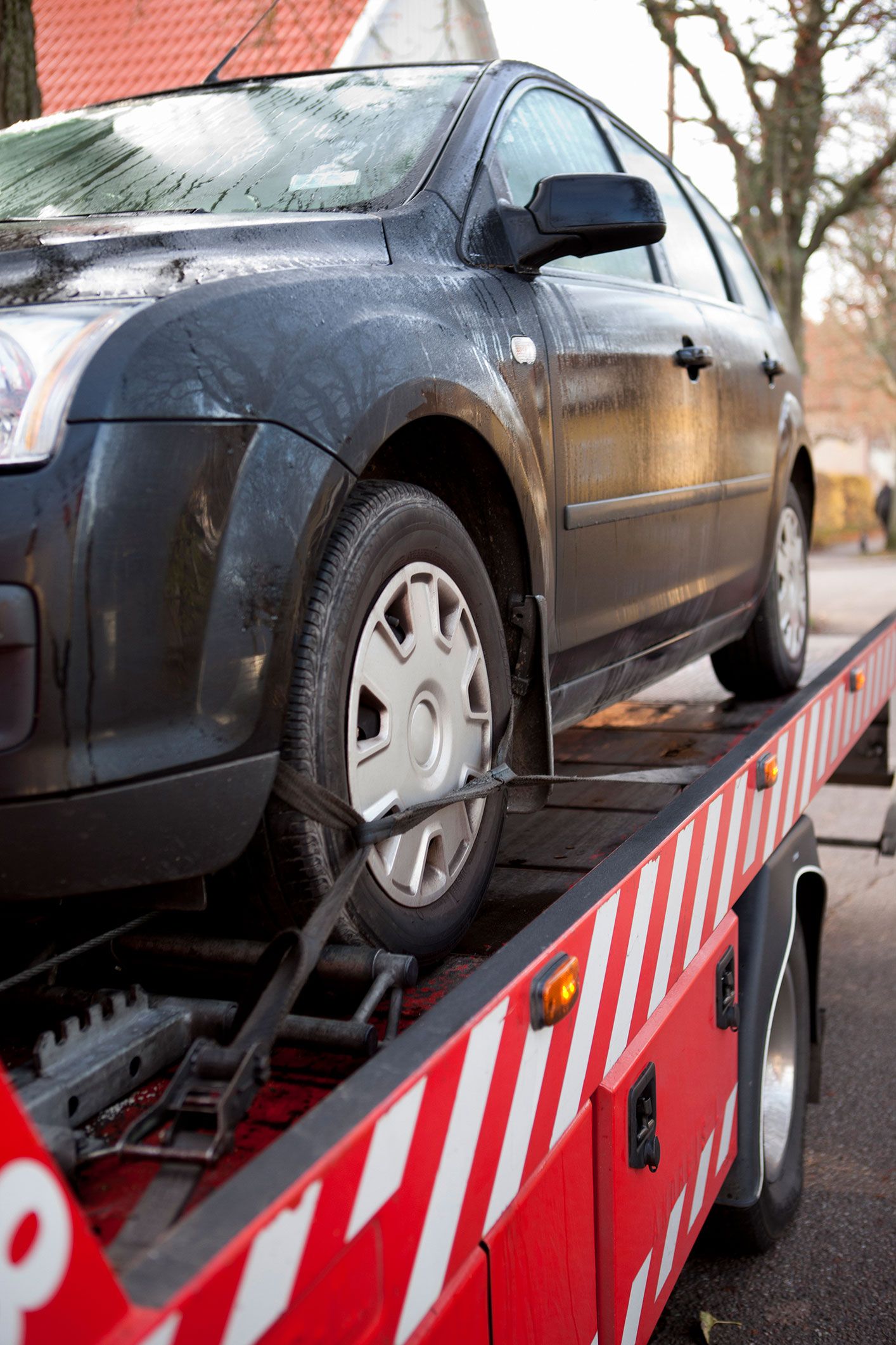 A black car is being towed by a tow truck. A black car is being towed by a tow truck.
