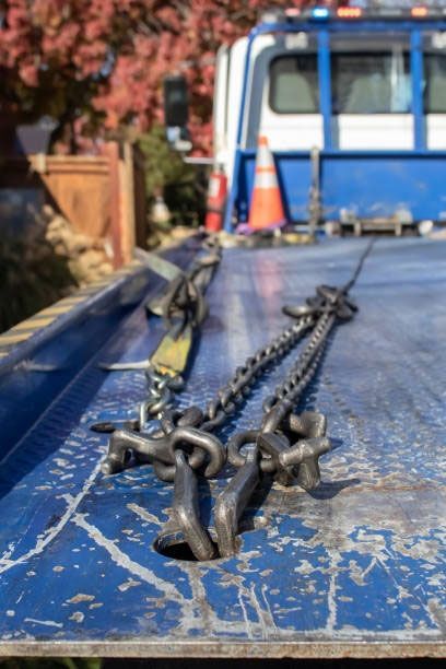 A blue tow truck with chains attached to the back of it.
