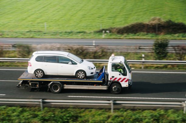A tow truck is towing a white van on a highway.