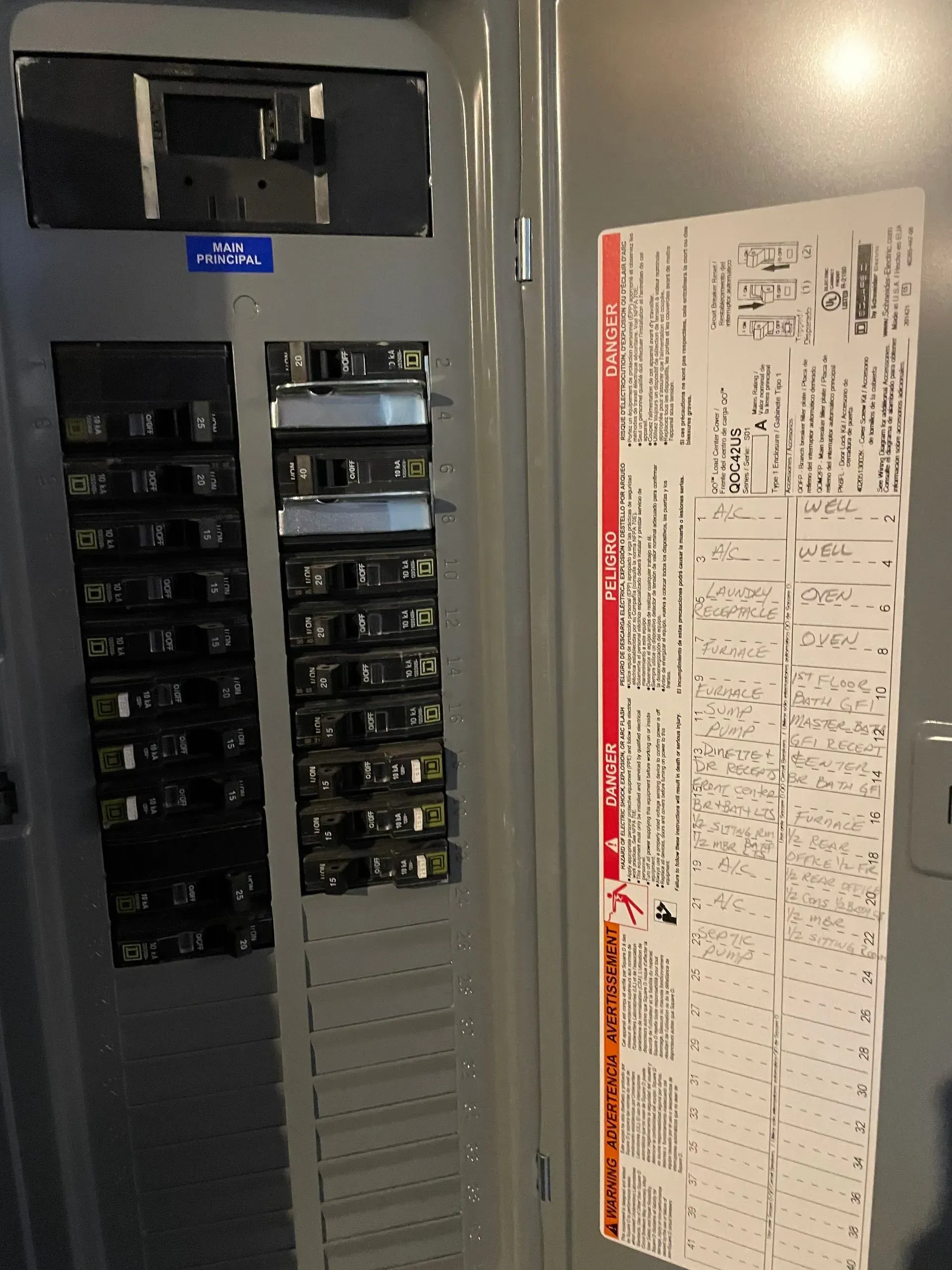 Open electrical service panel with a main breaker at the top, two columns of circuit breakers, and a wiring diagram label.