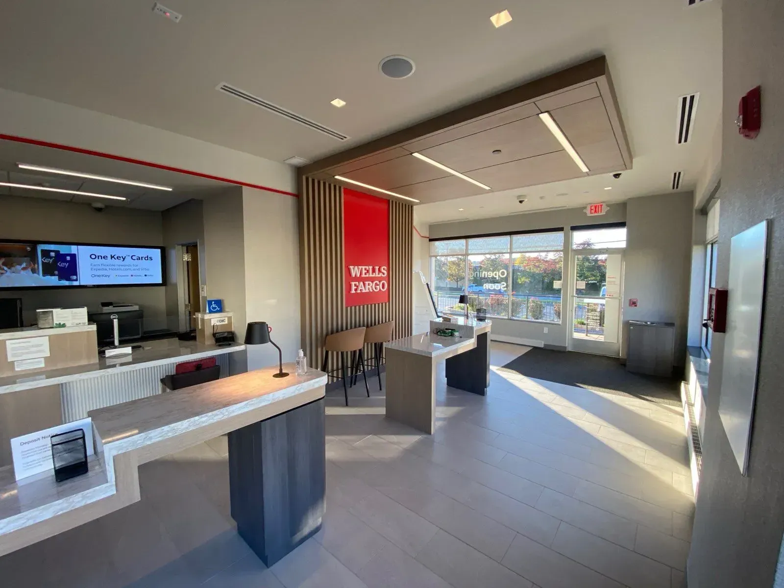 Modern Wells Fargo bank lobby interior with a reception desk, consultation area, and large windows with natural light.