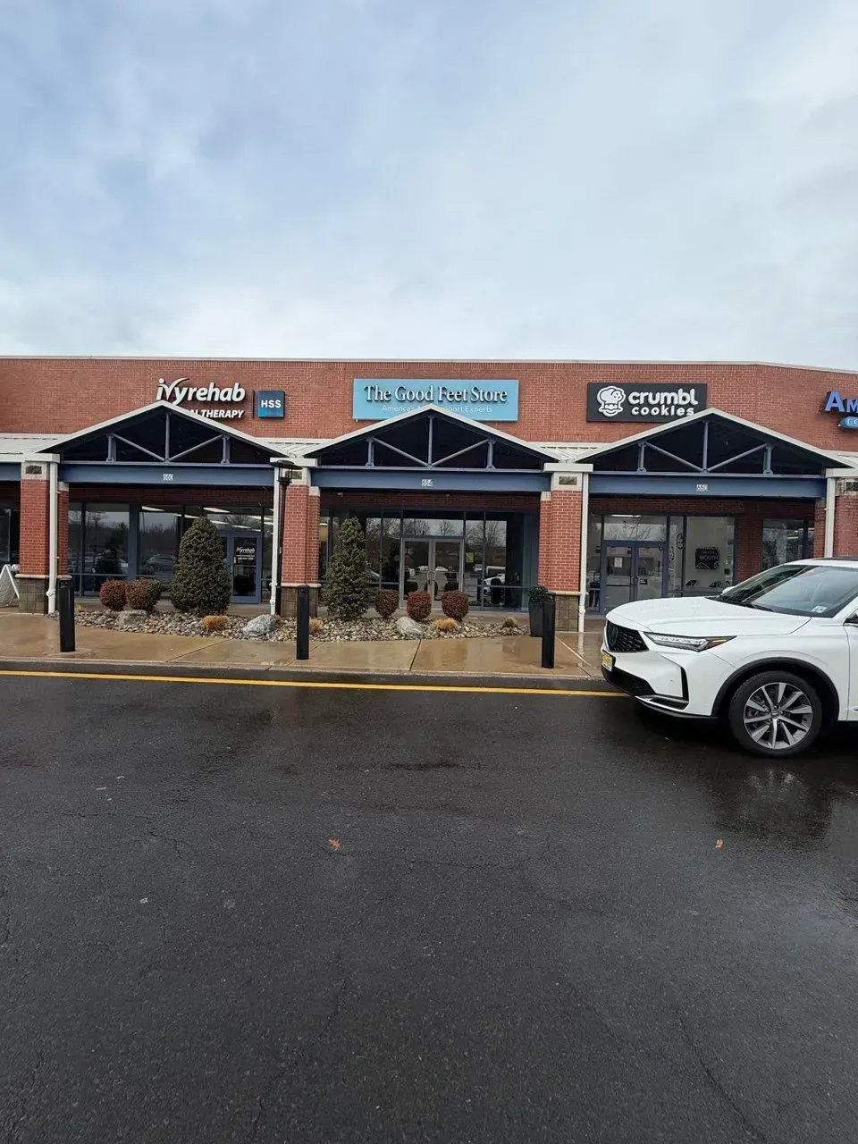A brick strip mall on an overcast day, featuring signs for 