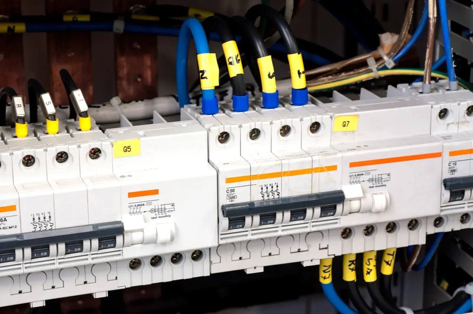A close-up view of electrical circuit breakers in a panel, featuring various labeled wires connected to modular switches.