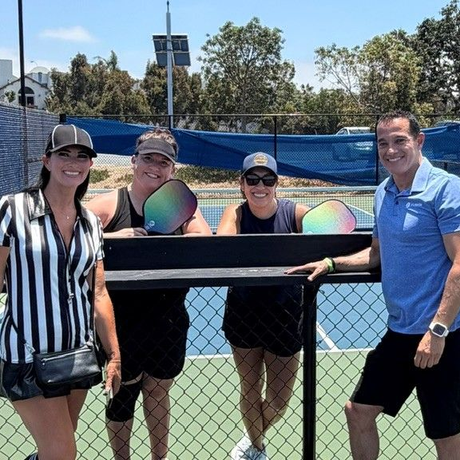 four people standing on a pickleball court.