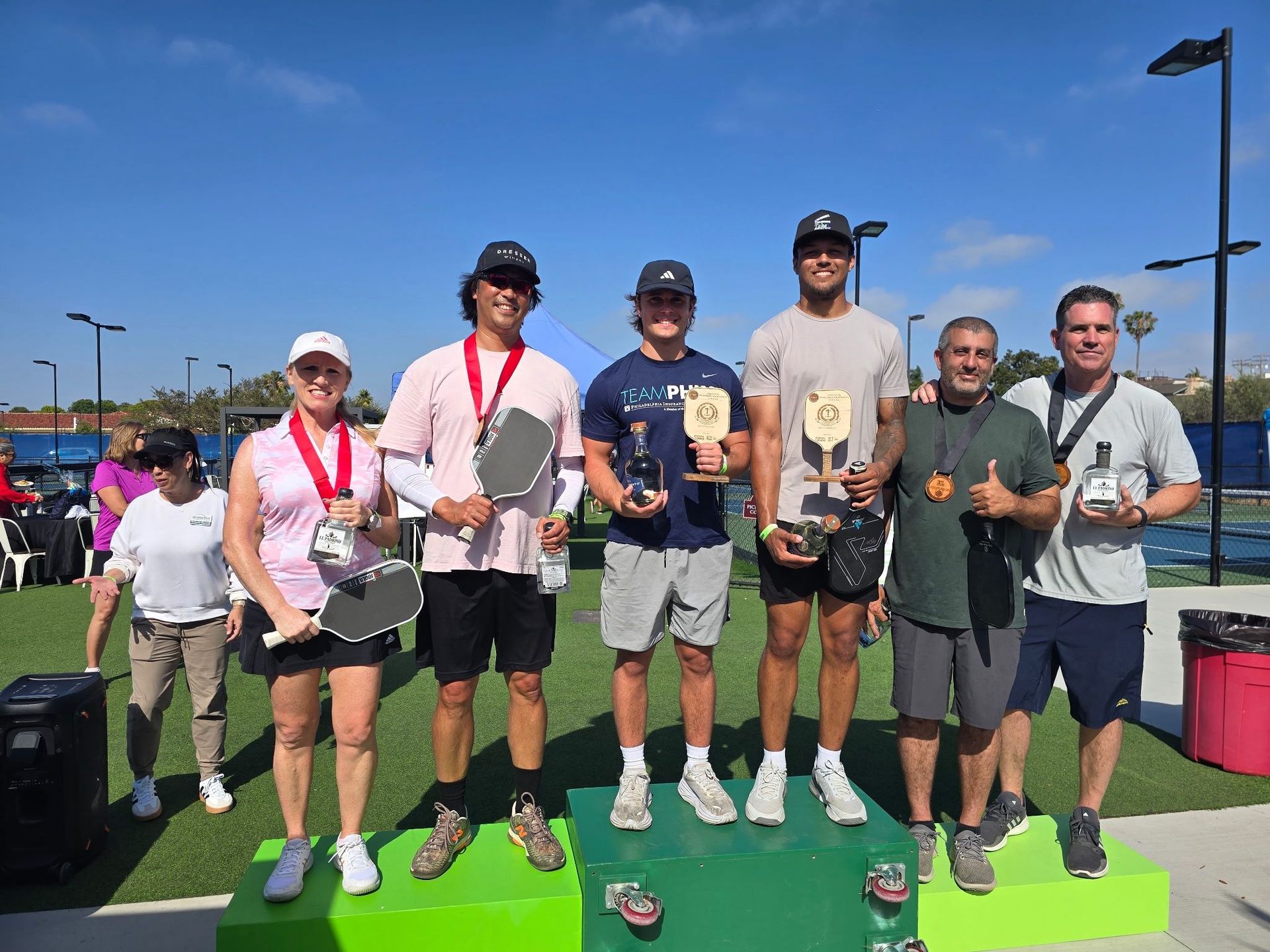 PWI 2026 Pickleball Tournament  - Beginners winning teams. Six adults with winners' ribbons stand on the podium.