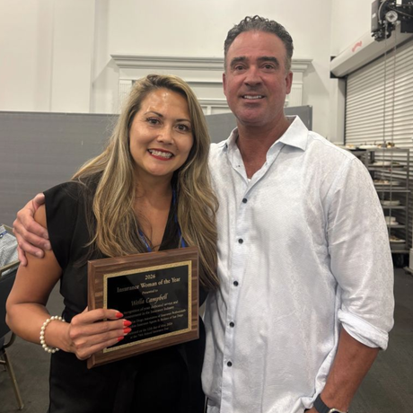 Wella Campbell holding the IIAB San Diego 2026 Woman of the Year plaque, standing next to a man.