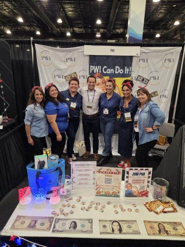 San Diego team of seven people standing in front of the PWI booth at I-Days