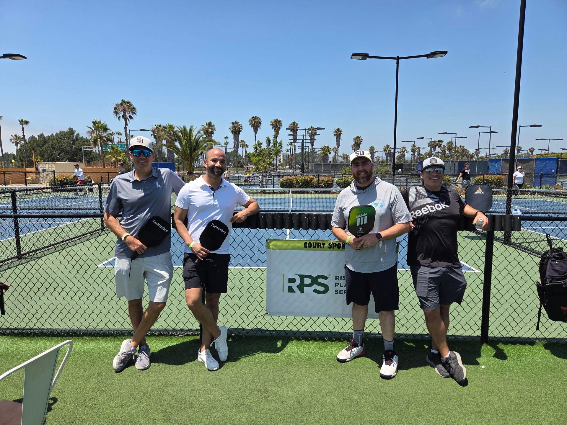PWI 2026 Pickleball Tournament - four members stand in front of RPS sponsor sign