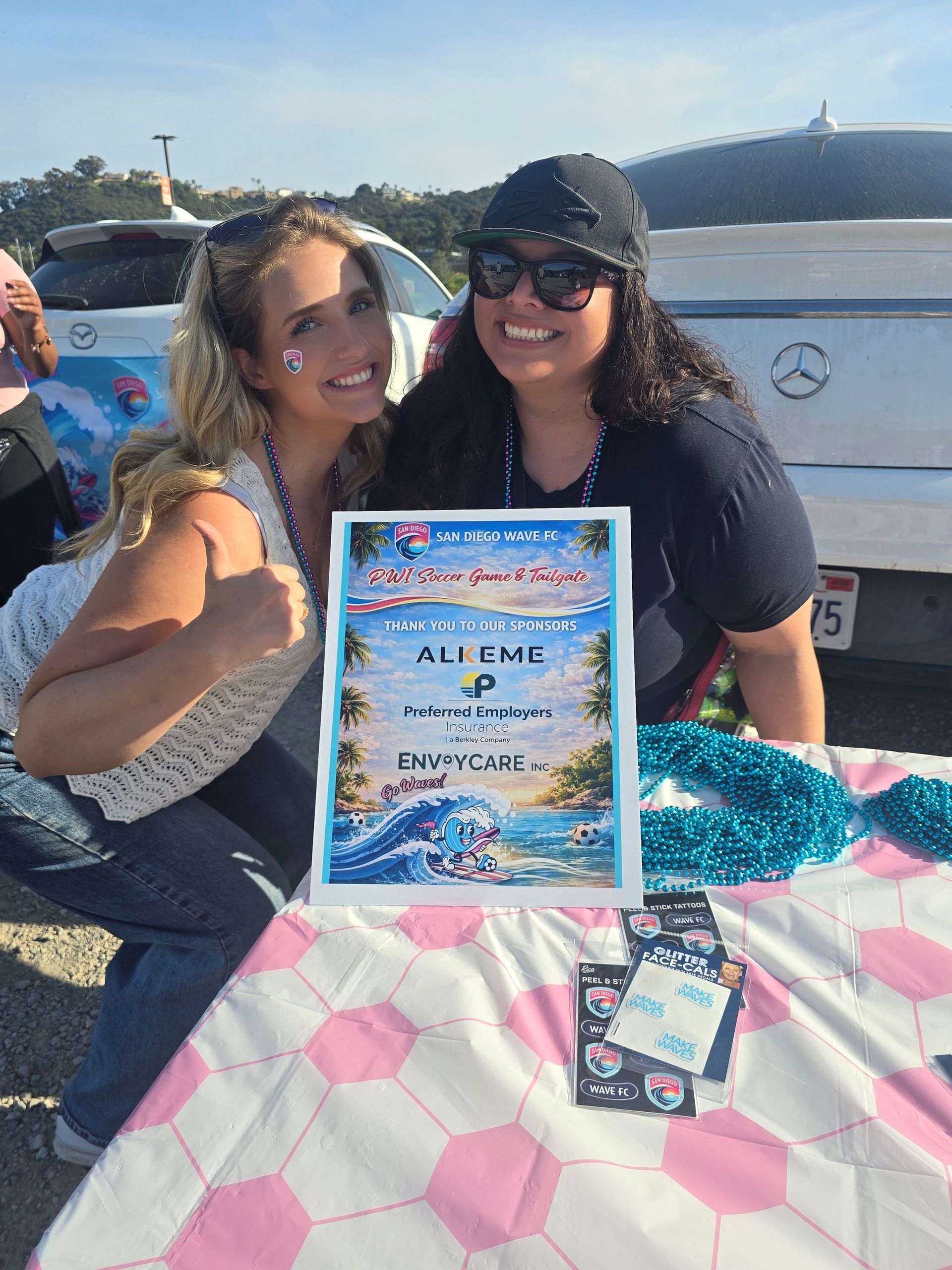 2026 Waves Soccer Game and Tailgate - Two members showing off the sponsor flyer