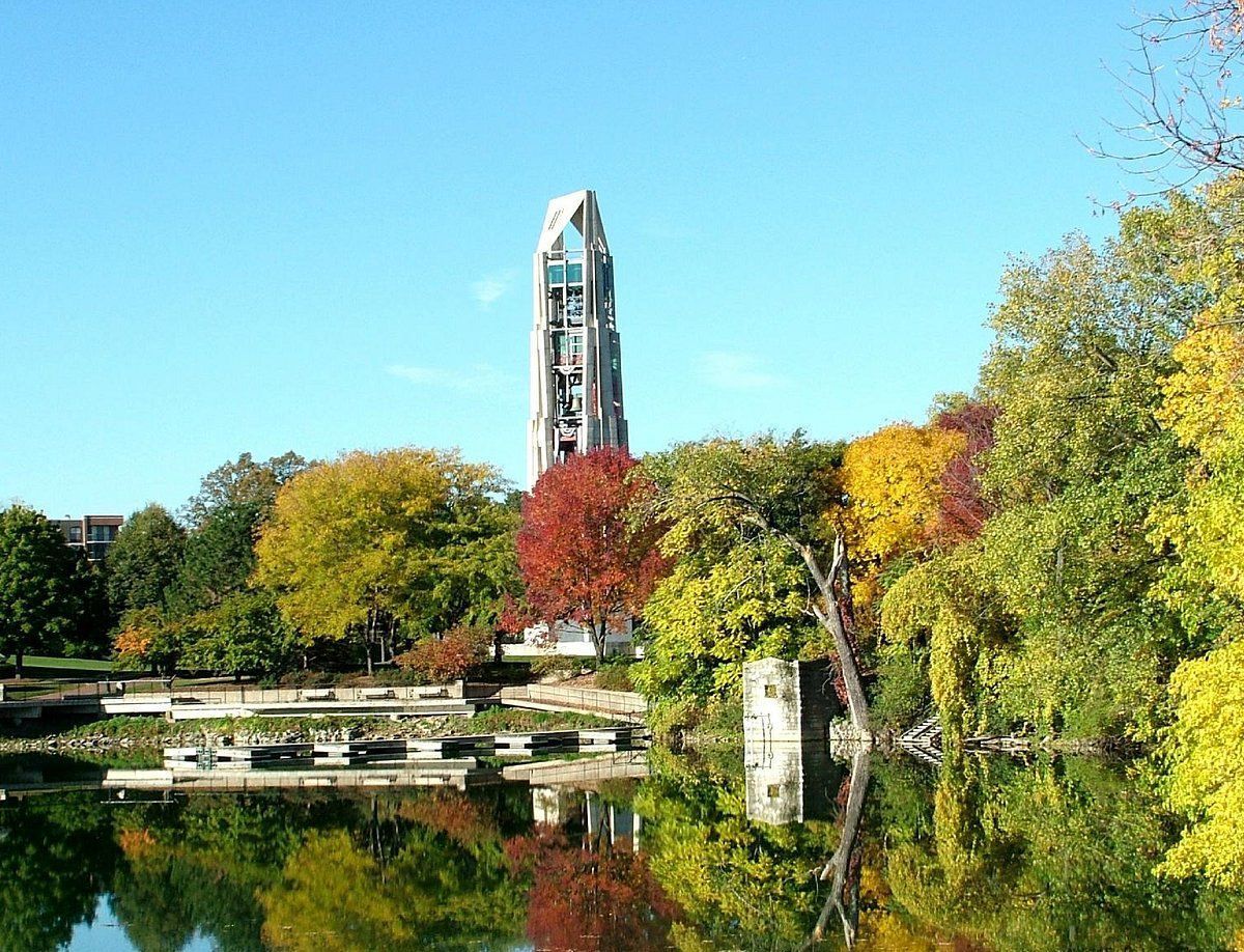 A tower is reflected in a lake surrounded by trees in Naperville Illinois