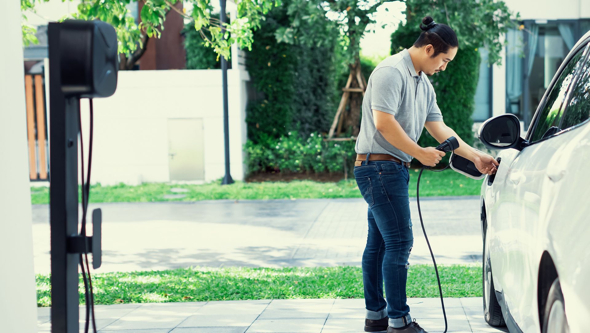 A man is charging his electric car at a charging station.