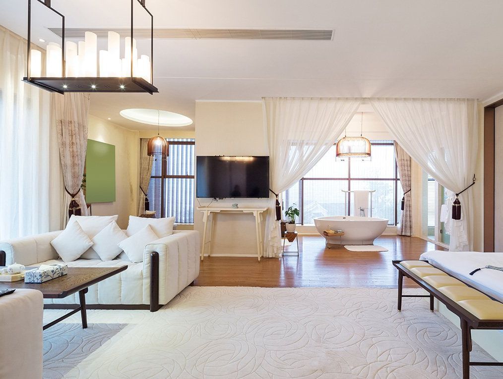 A living room with a couch , table , television and bathtub.