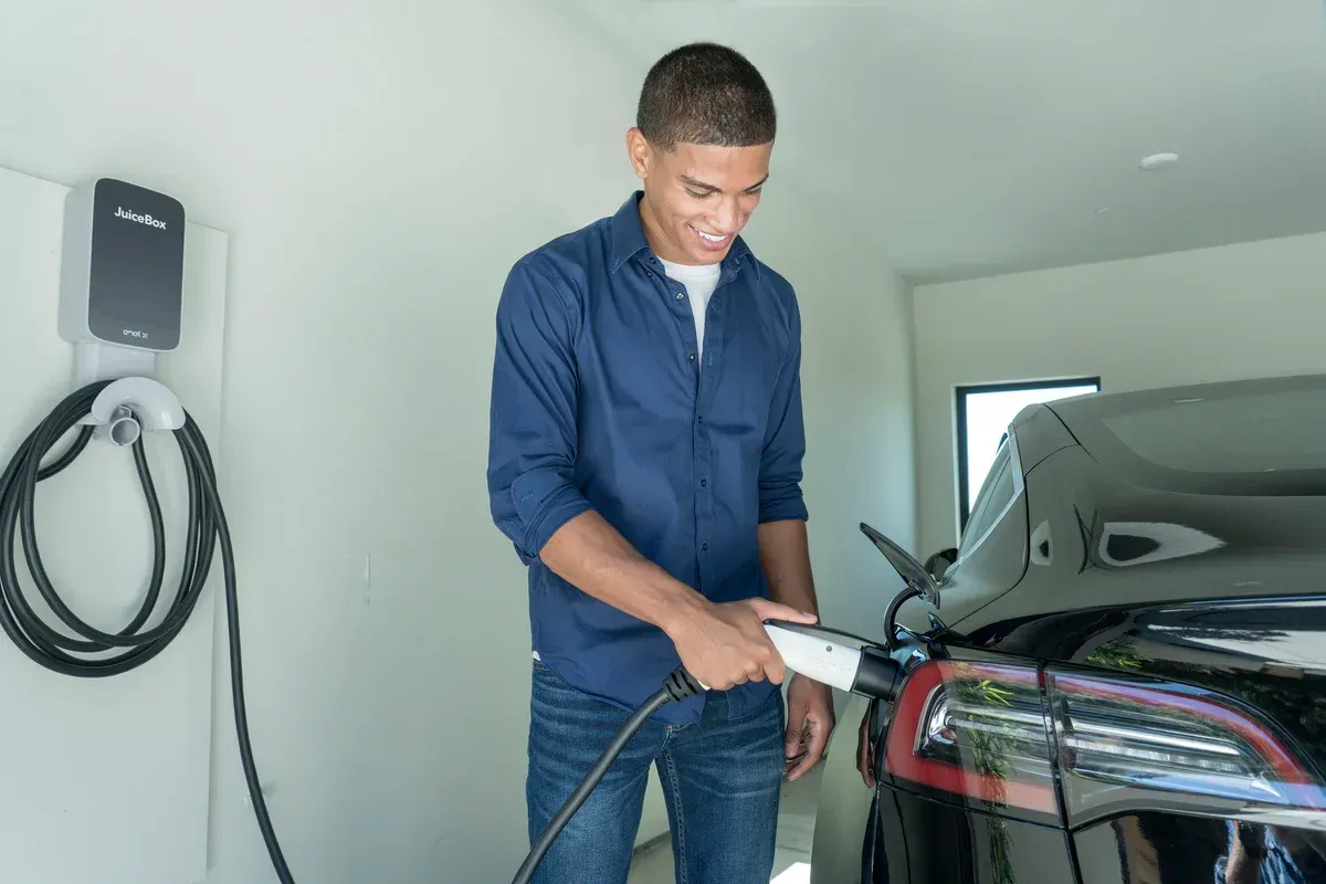 A man is charging an electric car in a garage.