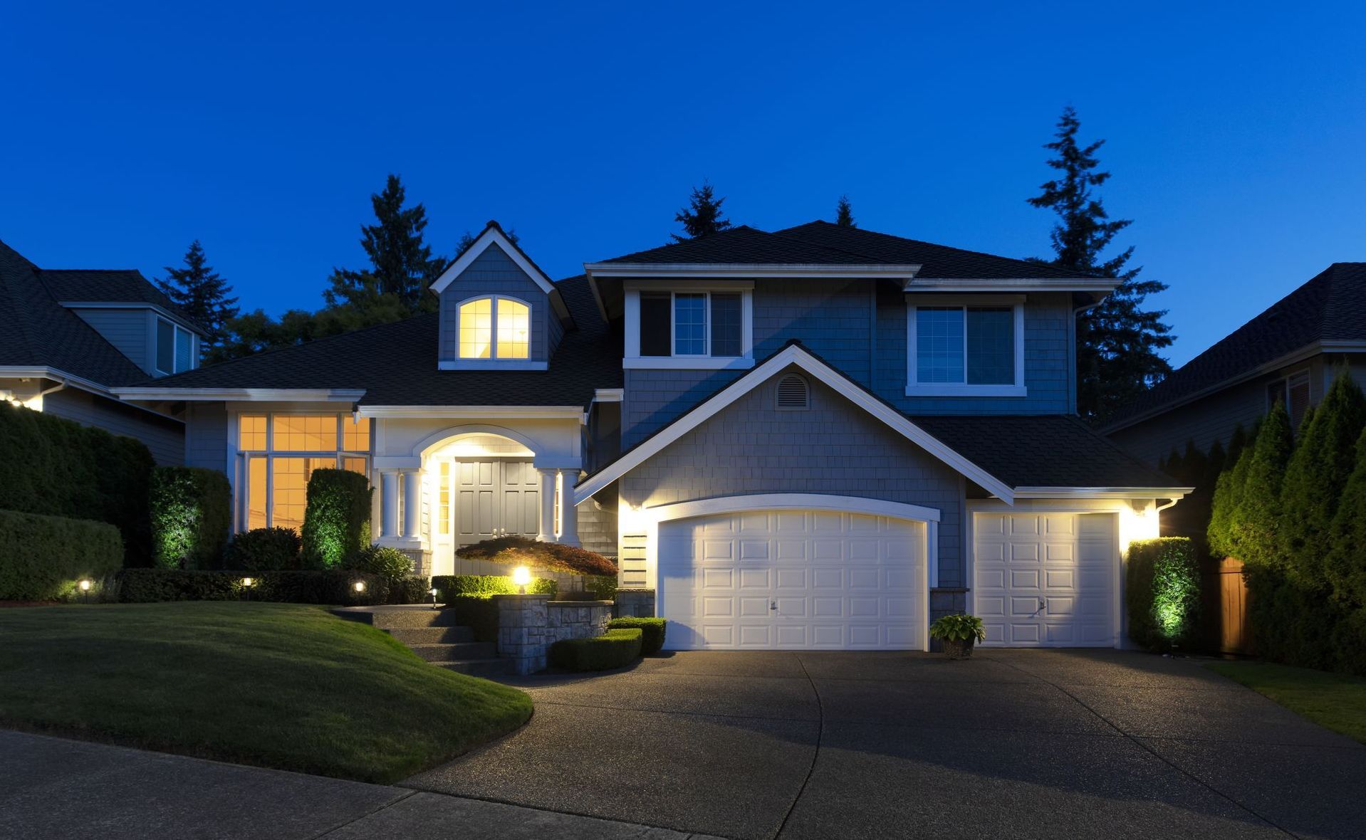 The house is lit up at night and has a large driveway.