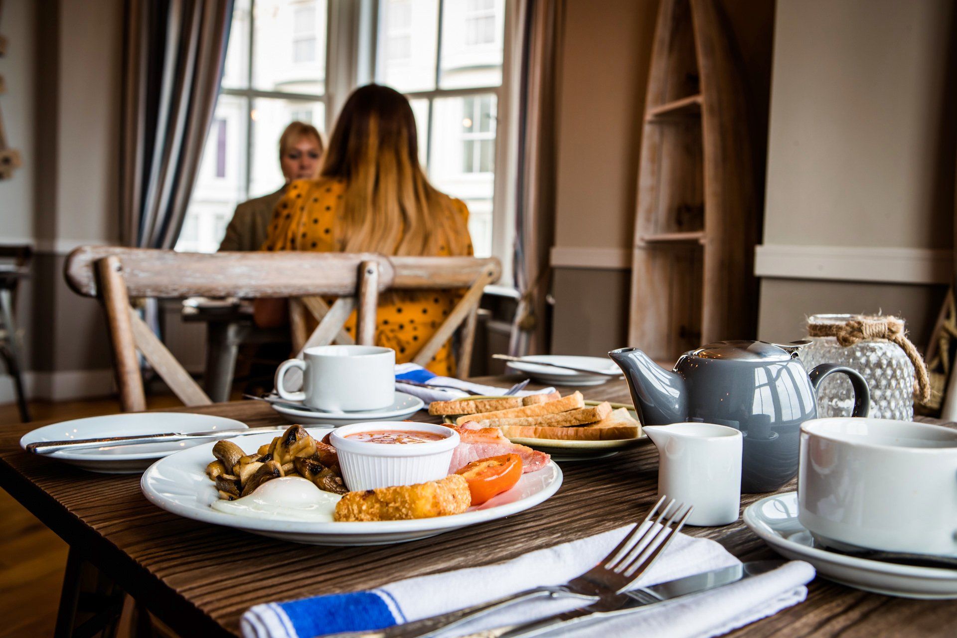 A woman is sitting at a table with a plate of food on it.