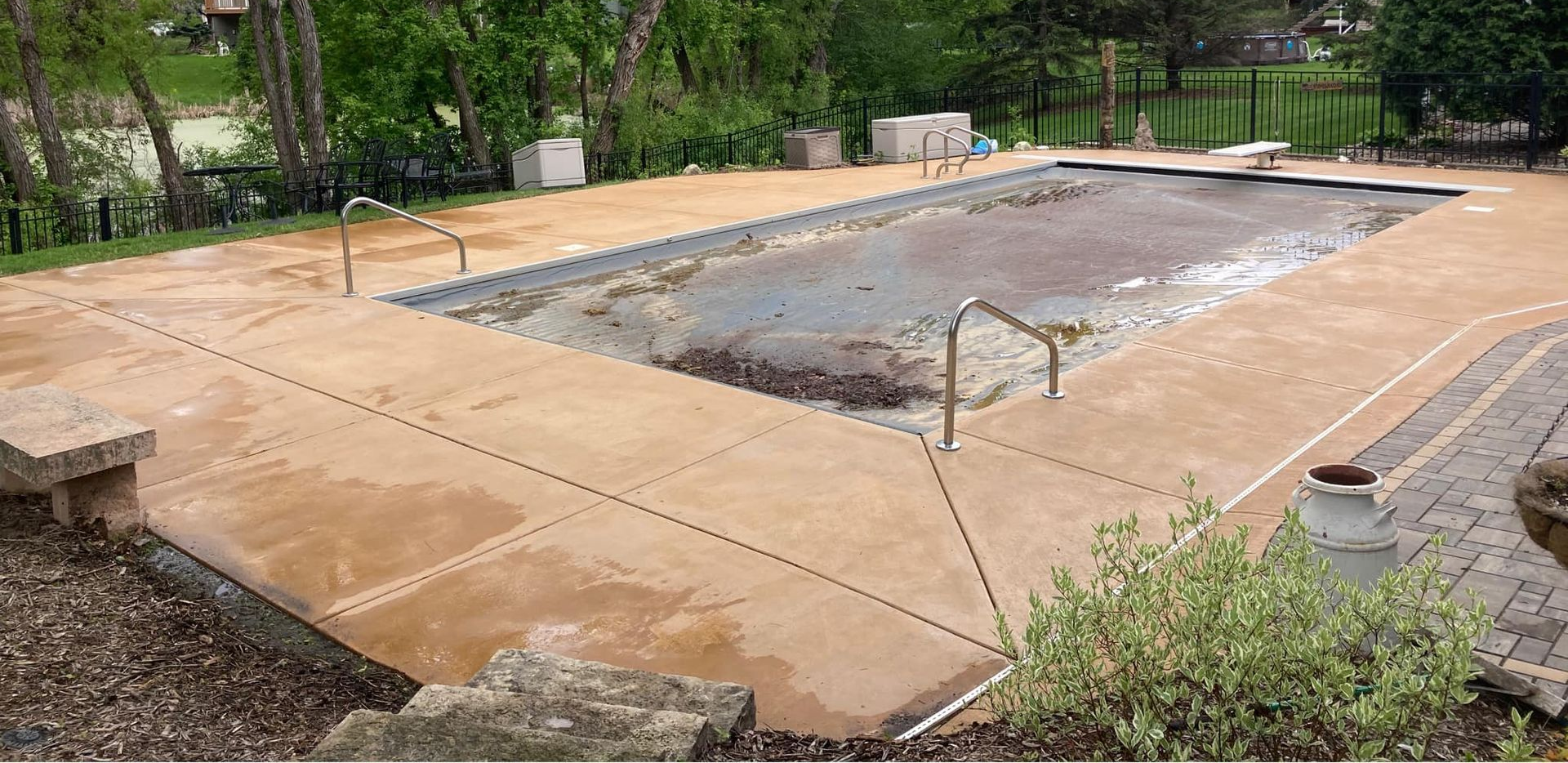 Concrete pool deck surrounding a pool with a tarp covering the water.