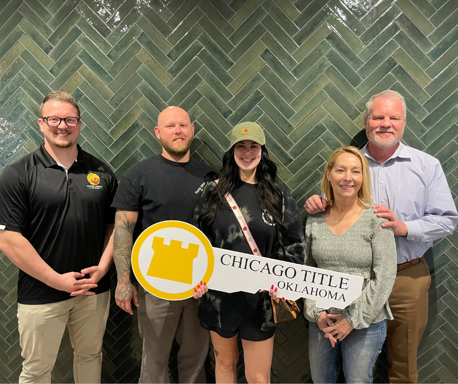 A group of people standing next to each other holding a sign that says chicago title oklahoma.