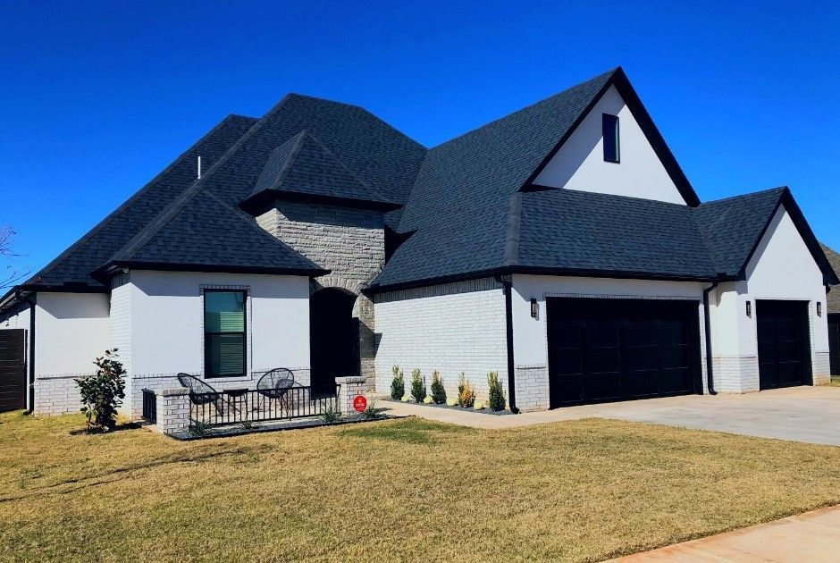 a large white house with a black roof and black garage doors