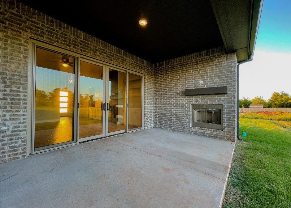 A patio with sliding glass doors and a fireplace in the backyard of a house.