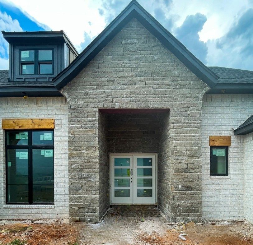 the front of a brick house with a black roof