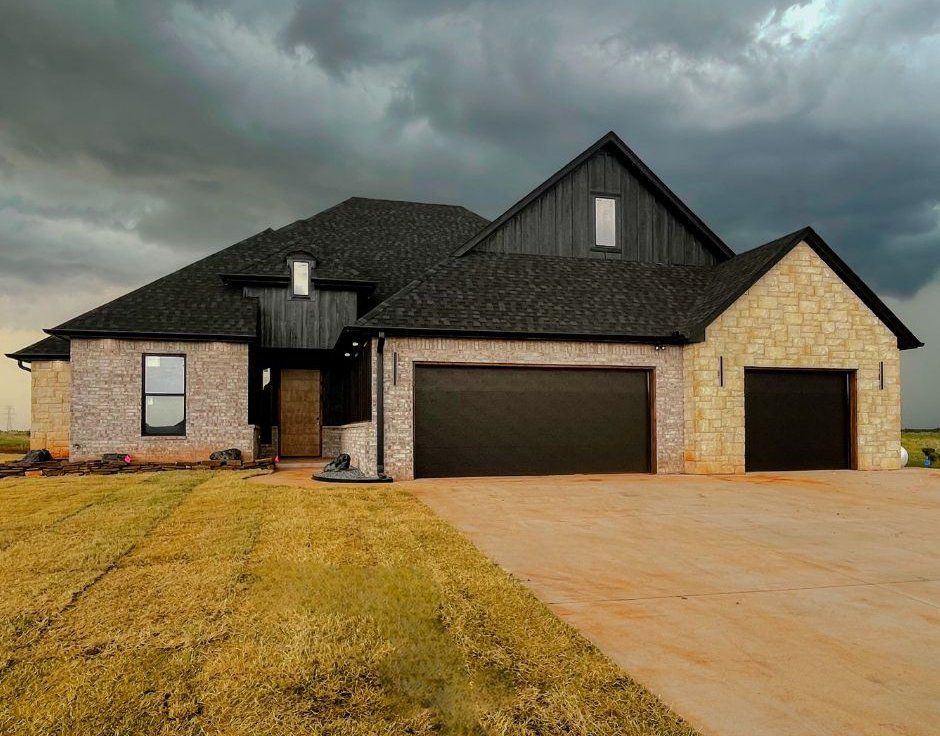 A large house with a black roof and two garage doors