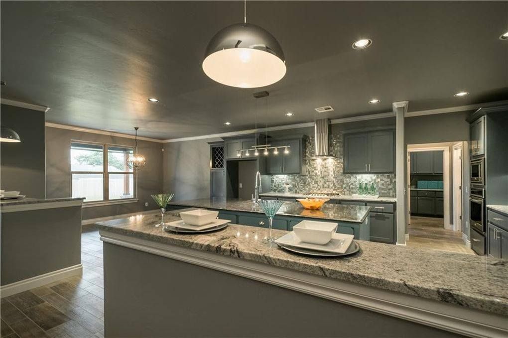 a kitchen with granite counter tops , gray cabinets , and a large island