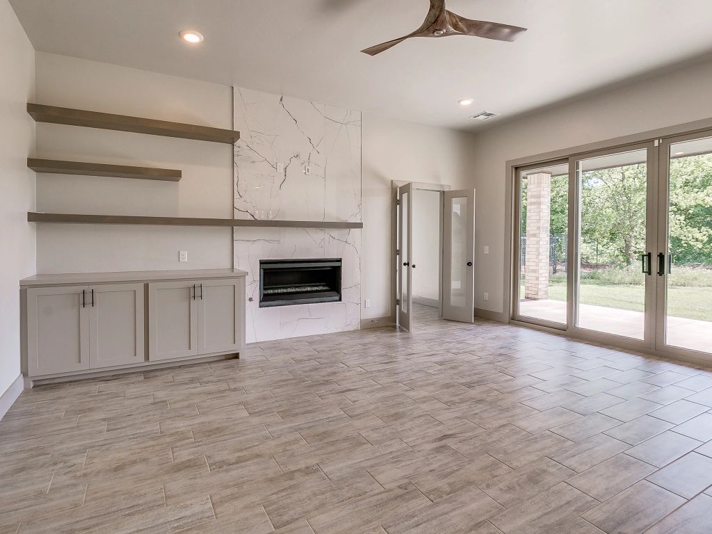 An empty living room with a fireplace and a ceiling fan.
