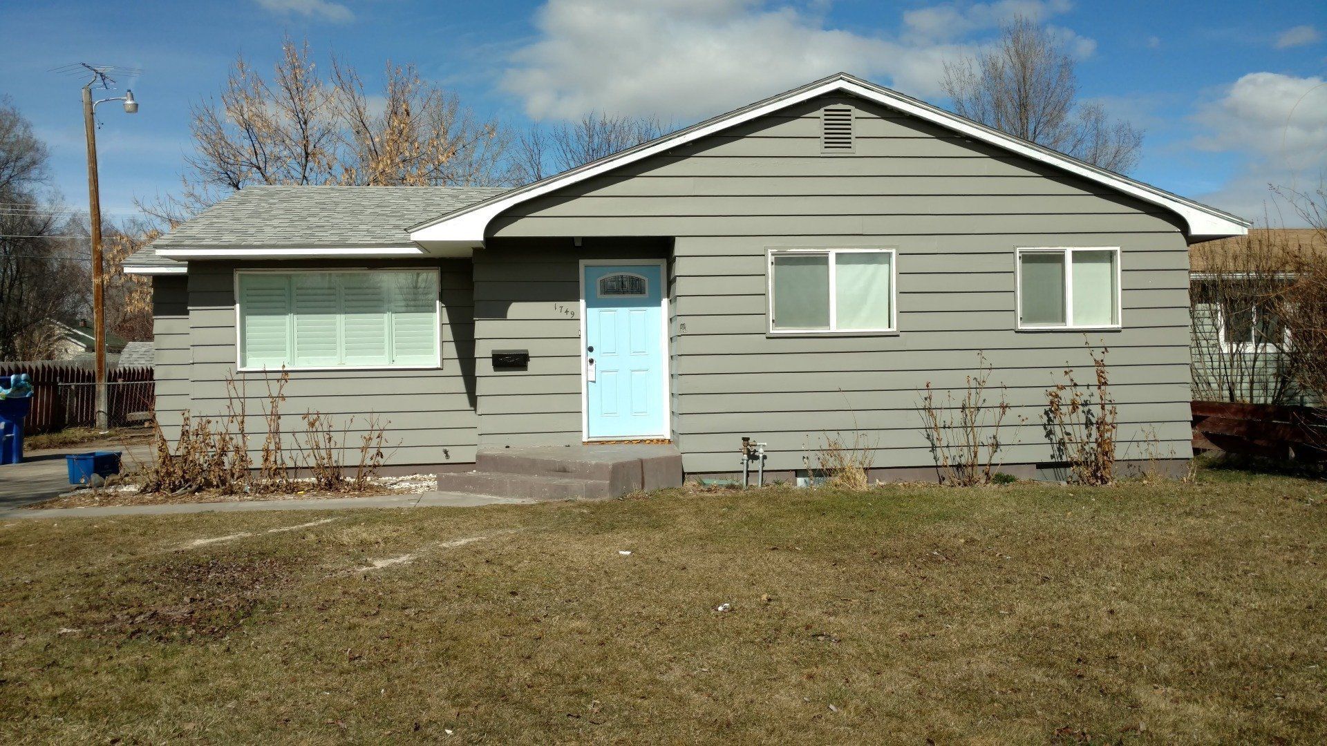 A gray house with a blue door and windows