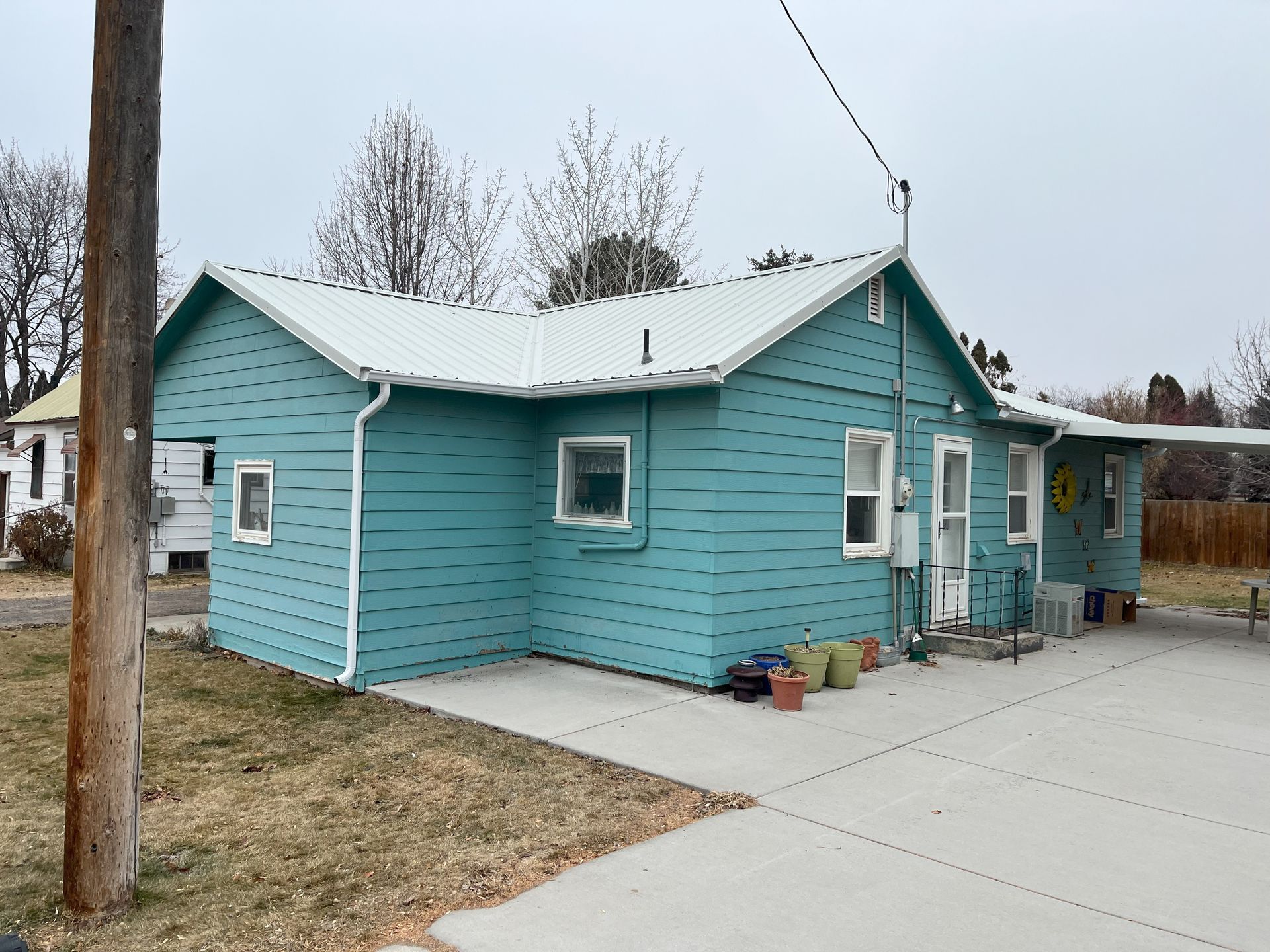 A blue house with a white roof and a concrete driveway
