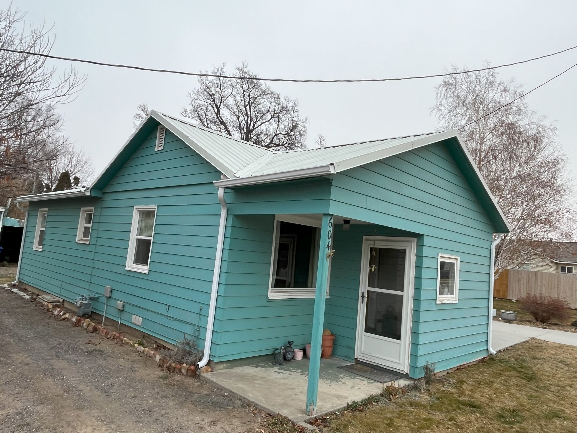 A small blue house with a white roof and a porch.