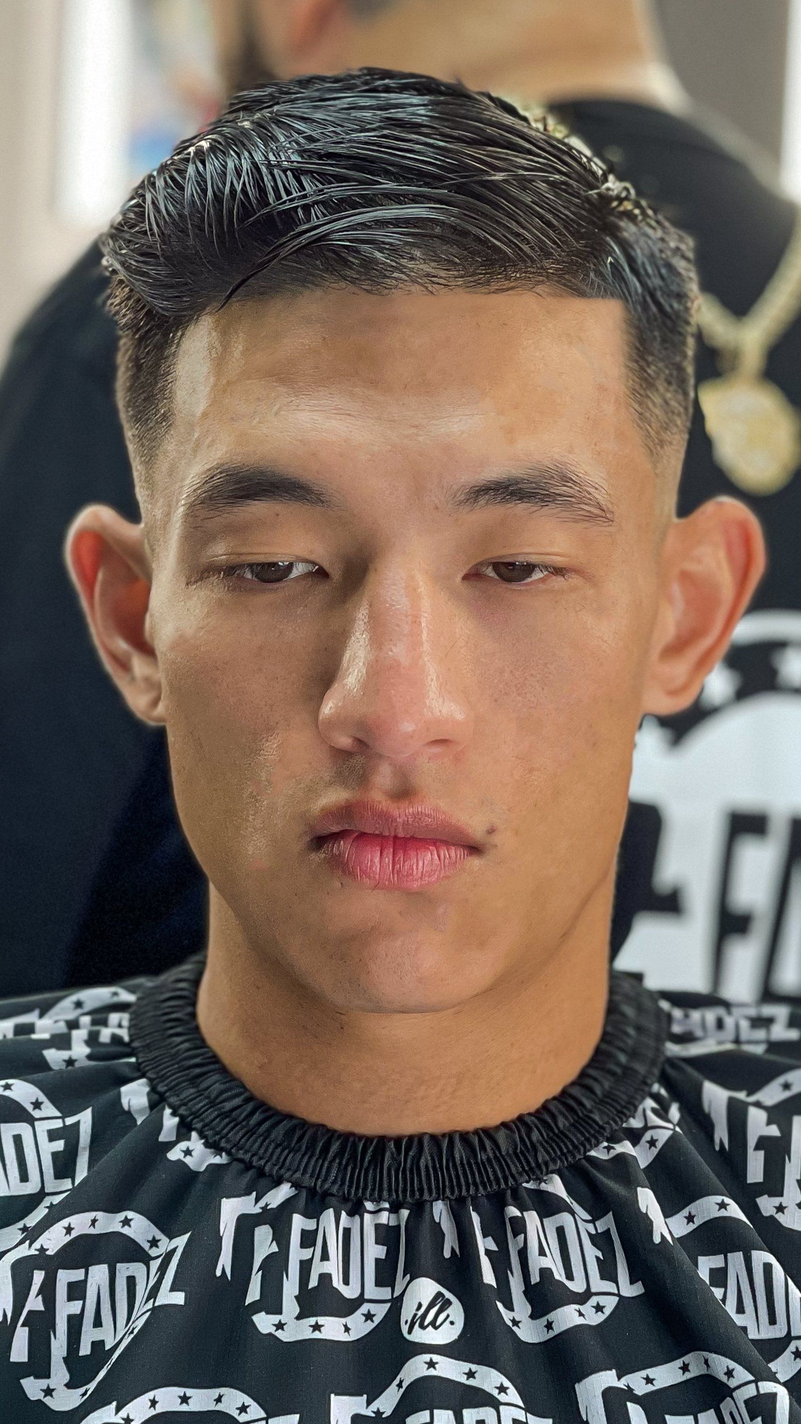 Close-up portrait of a person in a black patterned shirt with a neutral expression