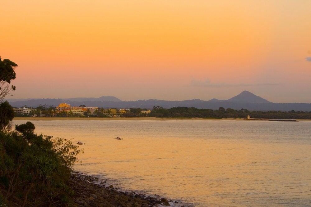 A Sunset Over A Body Of Water With Mountains In The Background — A2Z Property Services In Cooroy, QLD