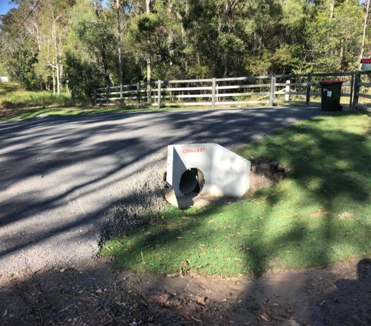 A Concrete Pipe Is Sitting In The Grass Next To A Road — A2Z Property Services In Woolooga, QLD