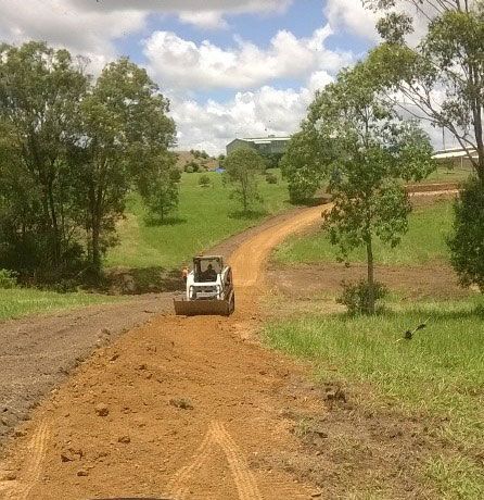 A Bulldozer Is Driving Down A Dirt Road In A Field — A2Z Property Services In Kybong, QLD