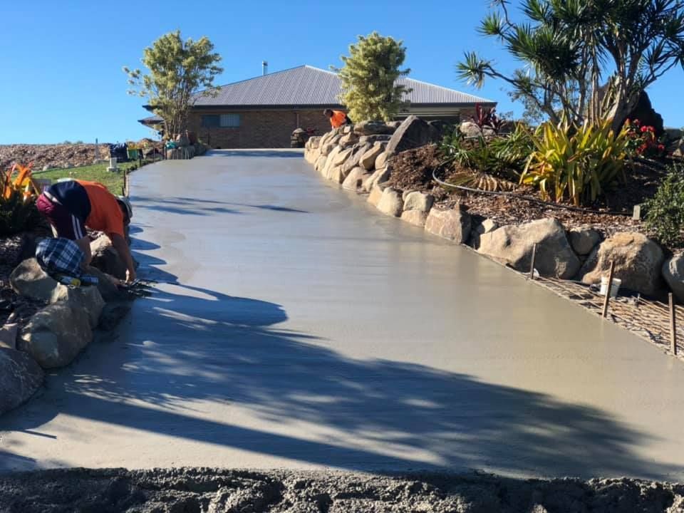 A Worker Smoothing Fresh Concrete Driveway Leading to A House — A2Z Property Services In Cooroy, QLD