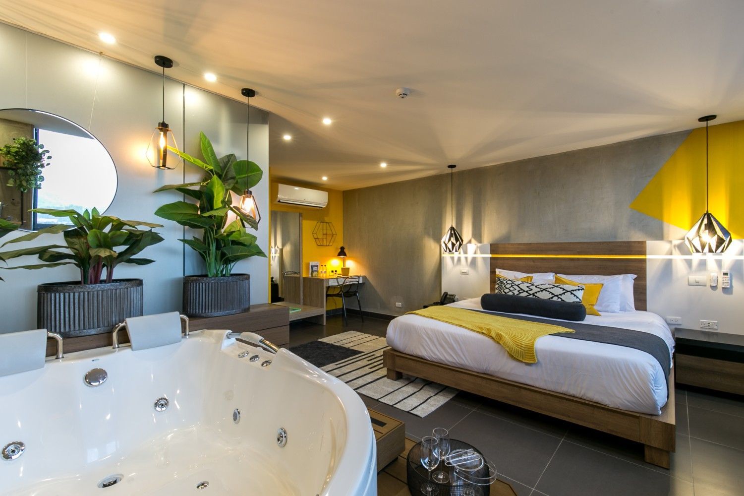 Suite de hotel de lujo con cama king size, bañera de hidromasaje e iluminación ambiental cálida.