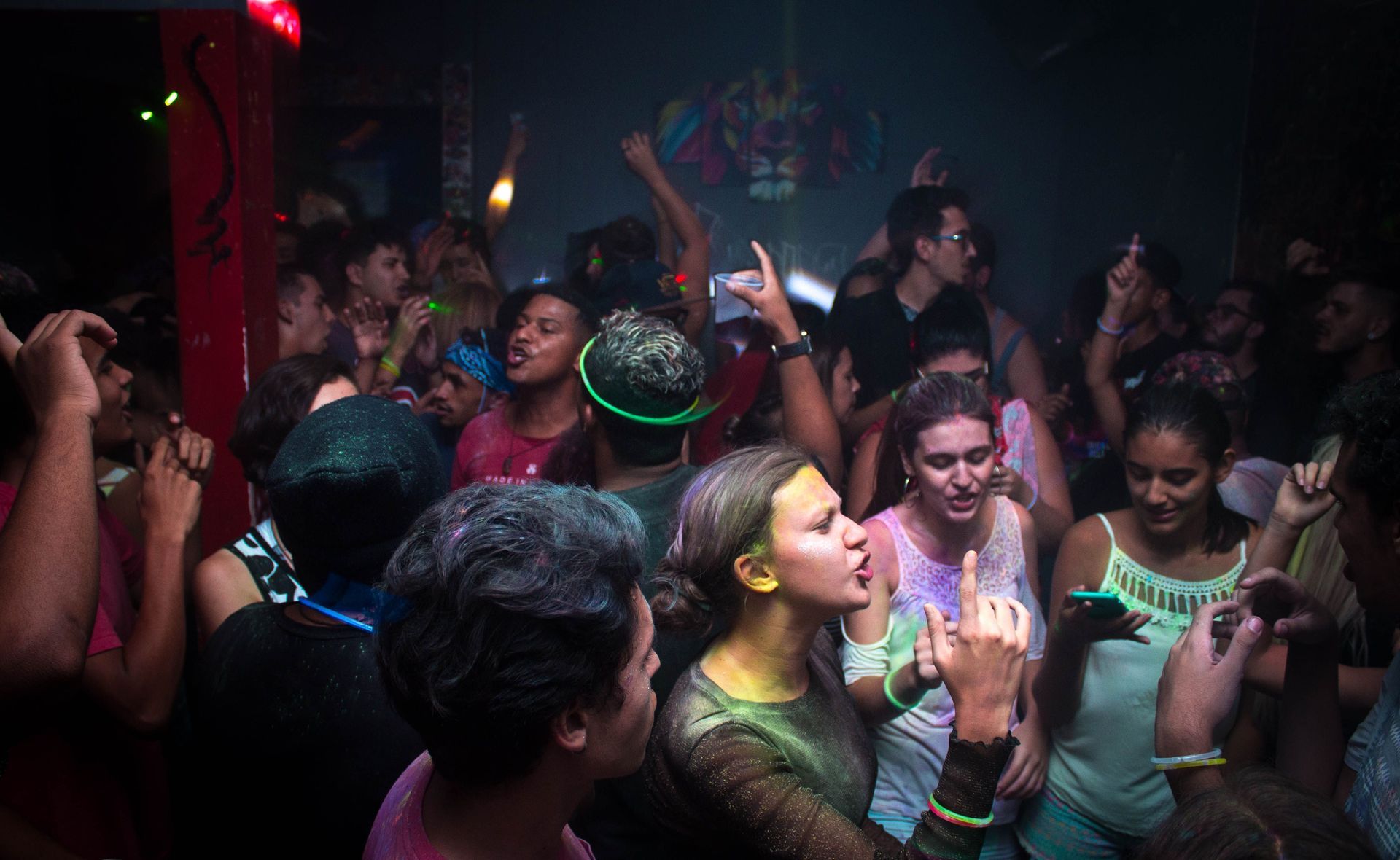 Pista de baile de discoteca abarrotada de gente animando bajo luces de neón de colores y una nube de humo.