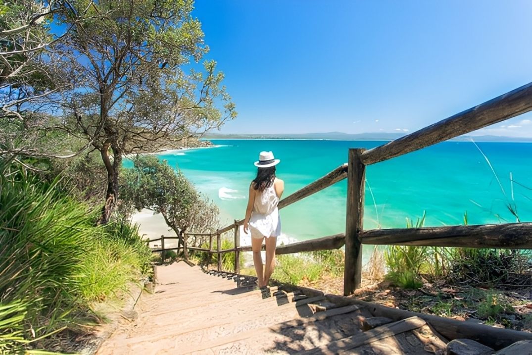Coastal view with turquoise water, rocky cliffs, and a light blue sky.