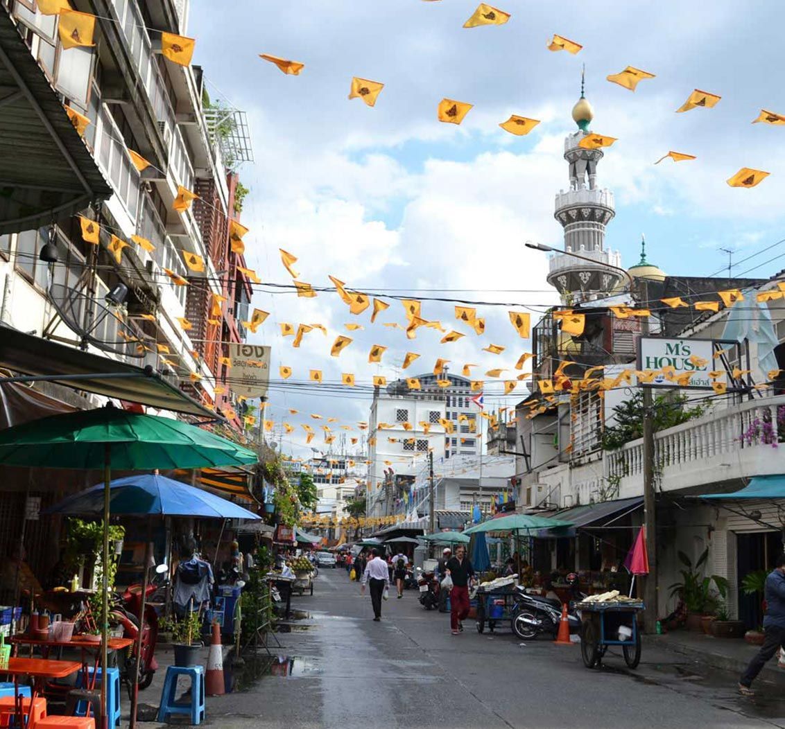 Street scene with shops, people, yellow flags, and a minaret.