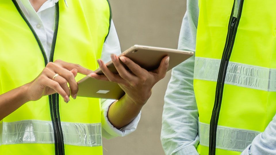 Person in a reflective vest using a tablet.